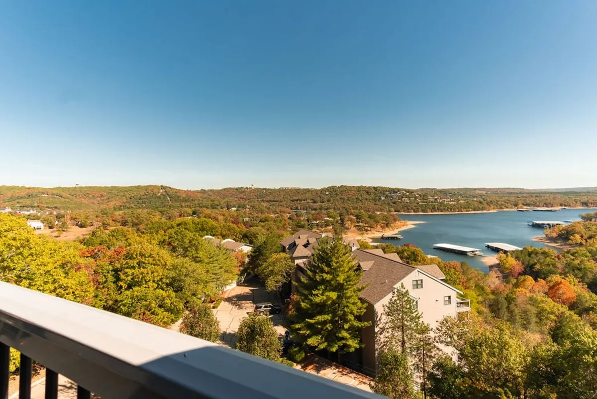 A tranquil waterfront view showcases a dock with boats, surrounded by autumn foliage and rolling hills. The serene setting highlights the lake’s proximity and offers visual cues for boating, nature walks, and seasonal changes.