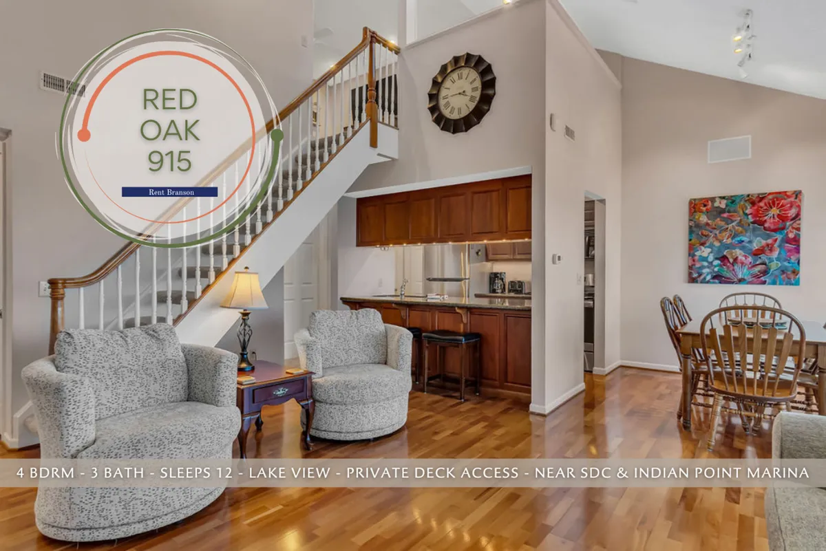 A wide-angle interior shot capturing the open staircase, a family-sized dining table, kitchen area, and a cozy seating area, all bathed in natural light. The image conveys a welcoming atmosphere, fit for both entertaining and daily living. The balcony access in the background hints at the extension of gathering spaces outdoors.