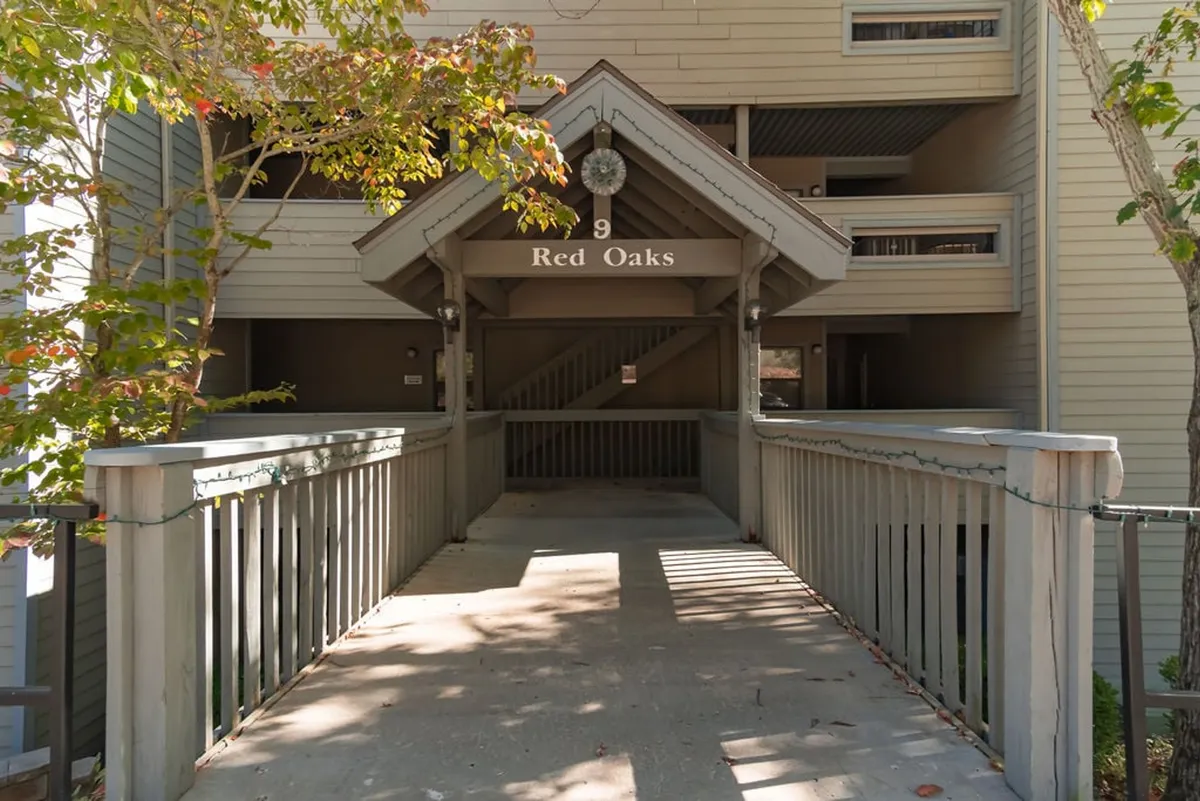 A welcoming exterior shot focusing on the entranceway and signage of the property, framed by surrounding trees. The scene suggests a sense of arrival and hints at the property's proximity to nature and local attractions.