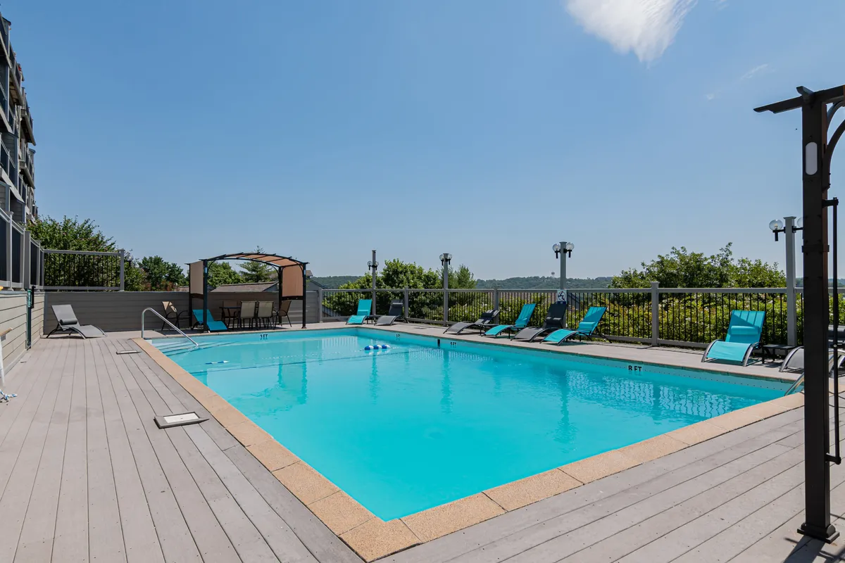 This image displays a sparkling outdoor swimming pool surrounded by lounge chairs and a shaded cabana, set against a backdrop of sunset lighting. The space looks inviting for swimming, sunbathing, and socializing, perfectly representing the resort’s main seasonal amenity.